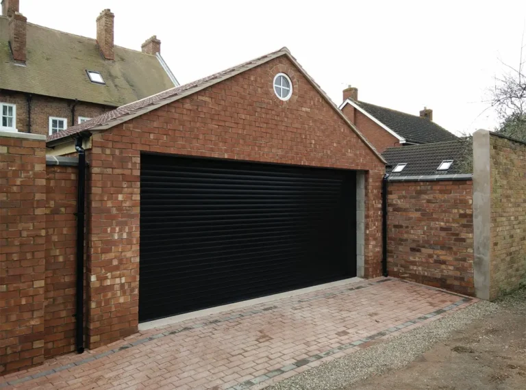 Black garage roller door complete installation on a modern residential home with sleek vertical slats and electric opener