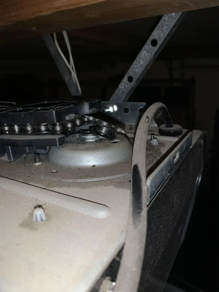 Broken garage door motor making an unusual sound, with a homeowner listening closely to the unit to identify the problem