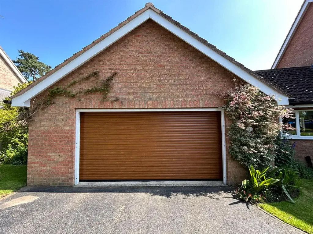Brown double-width roller garage door on a residential property with a warm finish and space-saving vertical rolling mechanism