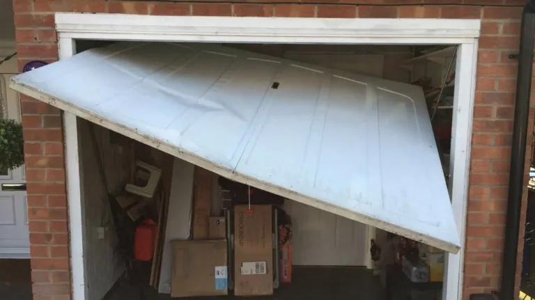 Common garage door issue showing a snapped cable on one side, with the door hanging unevenly and the broken cable visible
