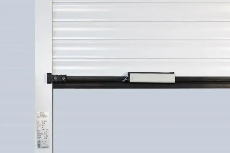 Garage door magnetic safety sensor mounted on a roller door curtain with magnets visible on the guide rail