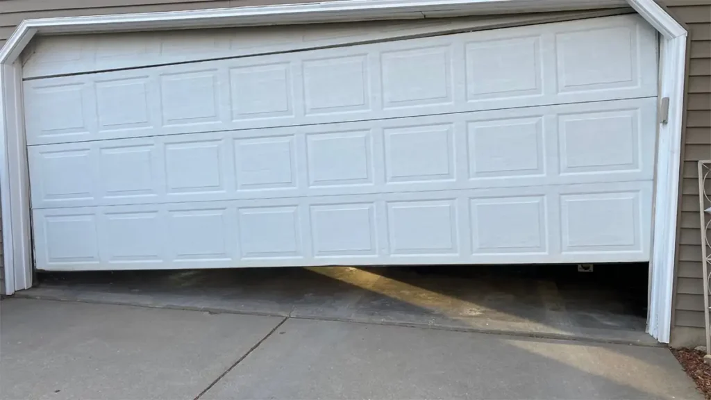Garage door off tracks on one side, showing the door hanging at an angle with a roller displaced from the guide rail on the affected side
