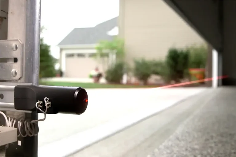 Garage door photoelectric safety sensor mounted on the door track near the floor
