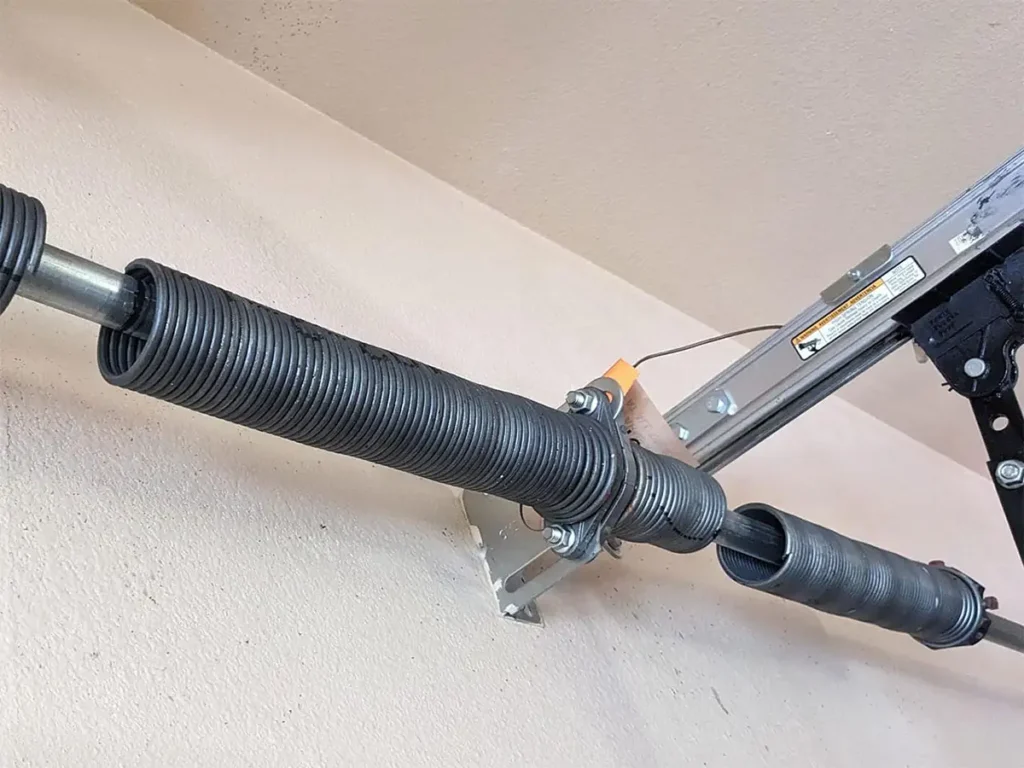 Garage door torsion spring snapped in half showing a clean break with a visible gap between the two pieces