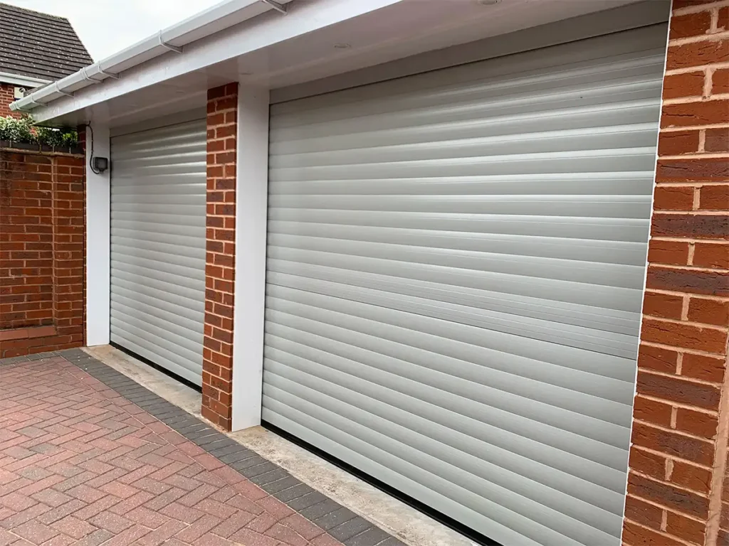 Light grey roller garage doors with white trim on a modern residential property featuring a clean, contemporary finish