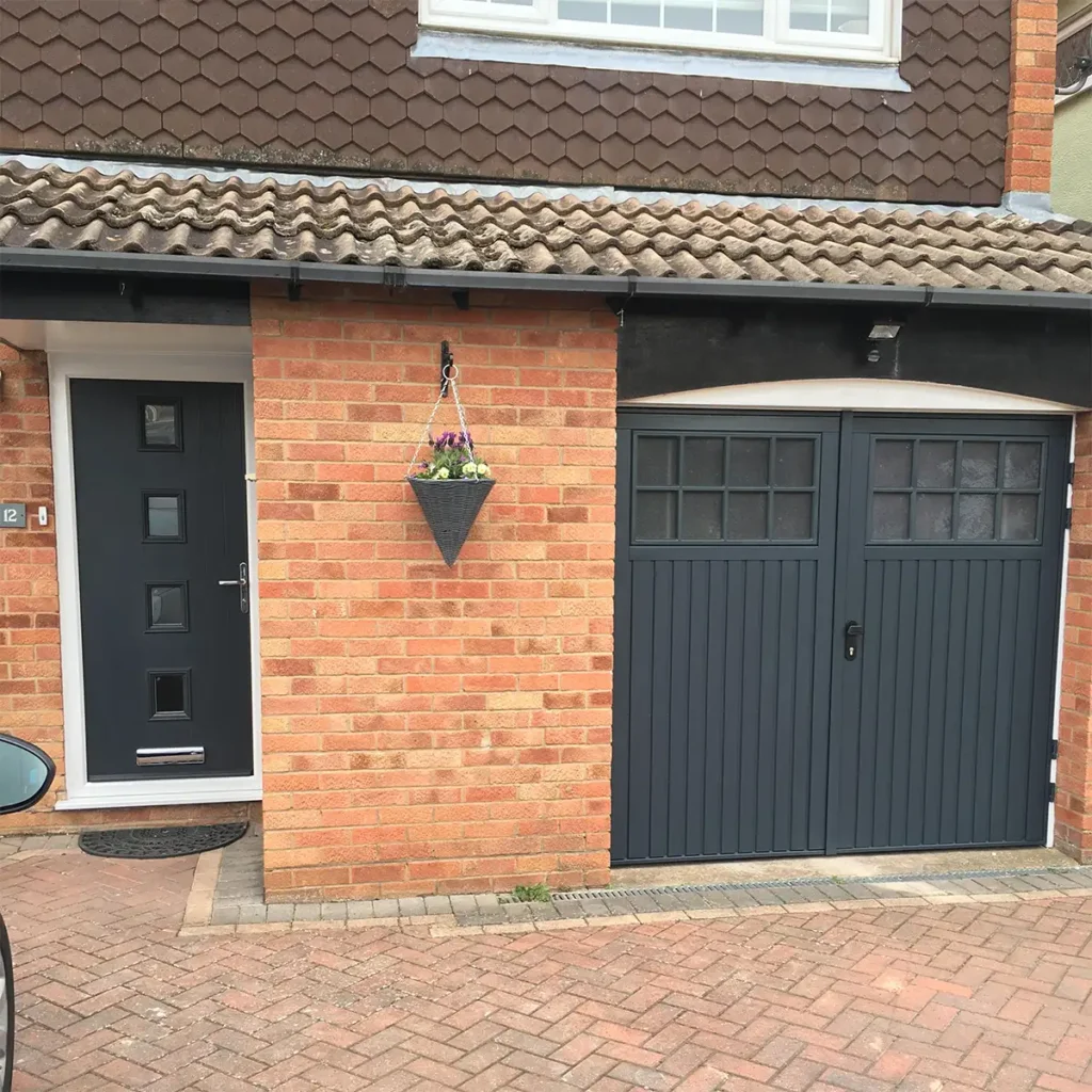 Matching front door and side-hinged garage door on a residential property with coordinated blue finish and traditional design