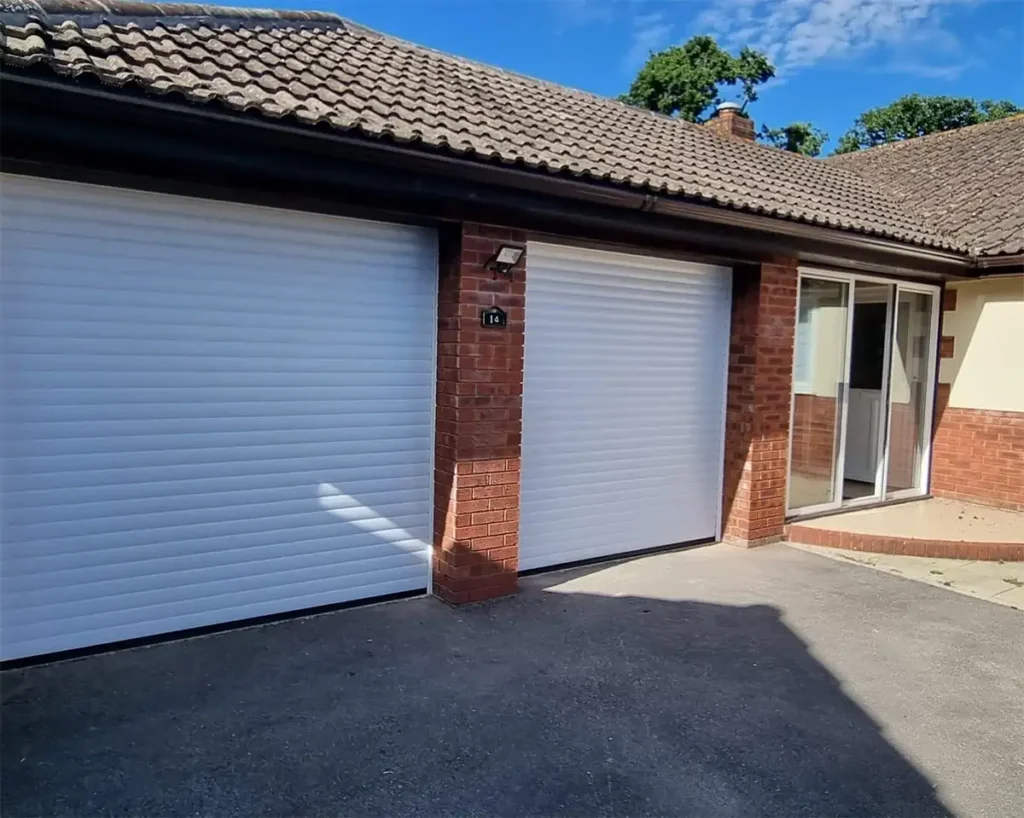 Original white twin single roller garage doors on a residential property with a clean, classic finish and space-saving vertical operation