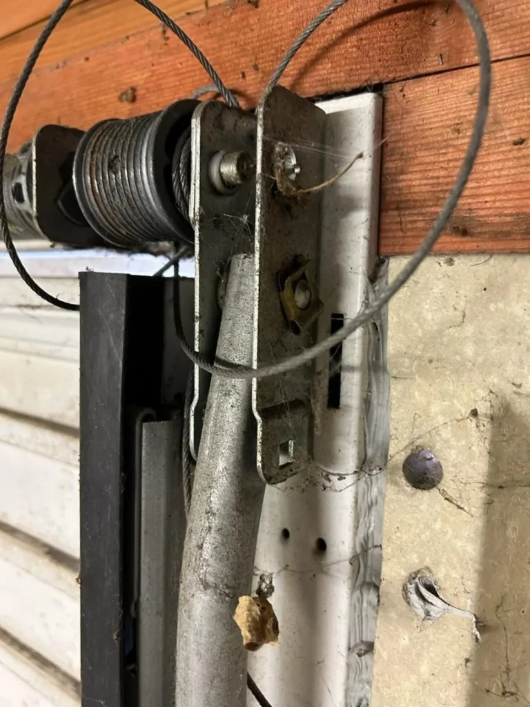 Snapped cable on an up-and-over garage door showing the broken cable and drum
