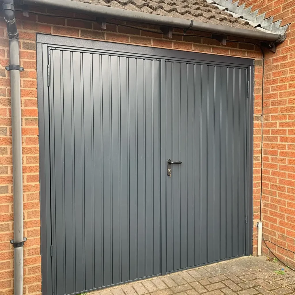 Steel side-hinged garage door in grey on a residential property with a clean, modern finish and traditional opening mechanism