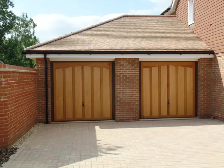 Twin timber up-and-over garage door on a residential property with a natural wood finish and traditional panelled design