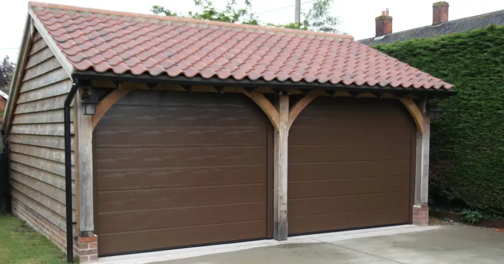 Twin brown coloured sectional garage doors made of steel fitted to a residential property with a warm, traditional finish