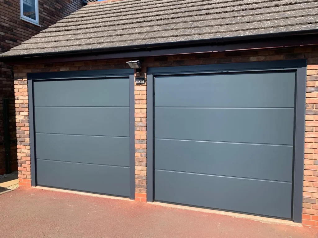 Twin aluminium sectional garage doors on a modern home with sleek silver-grey finish and contemporary panel design