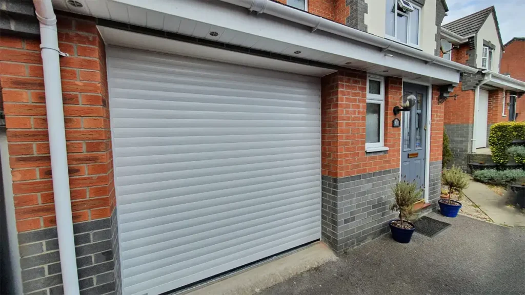 White single roller garage door on a residential property with a clean, classic finish and space-saving vertical rolling mechanism
