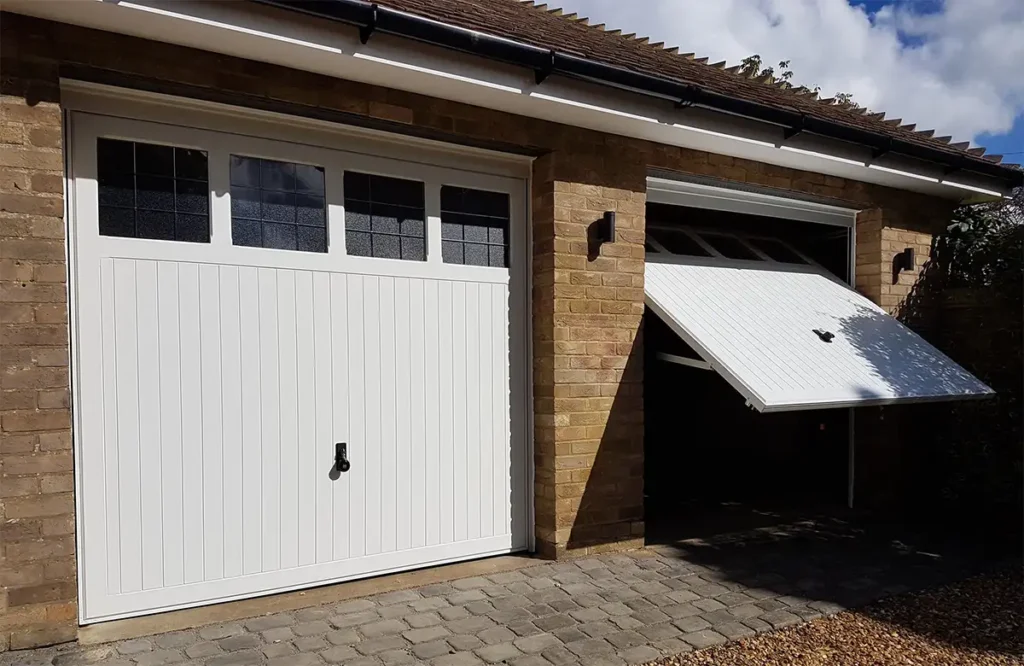 White up-and-over garage door with windows on a residential property featuring a classic panelled design and glazed inserts for natural light